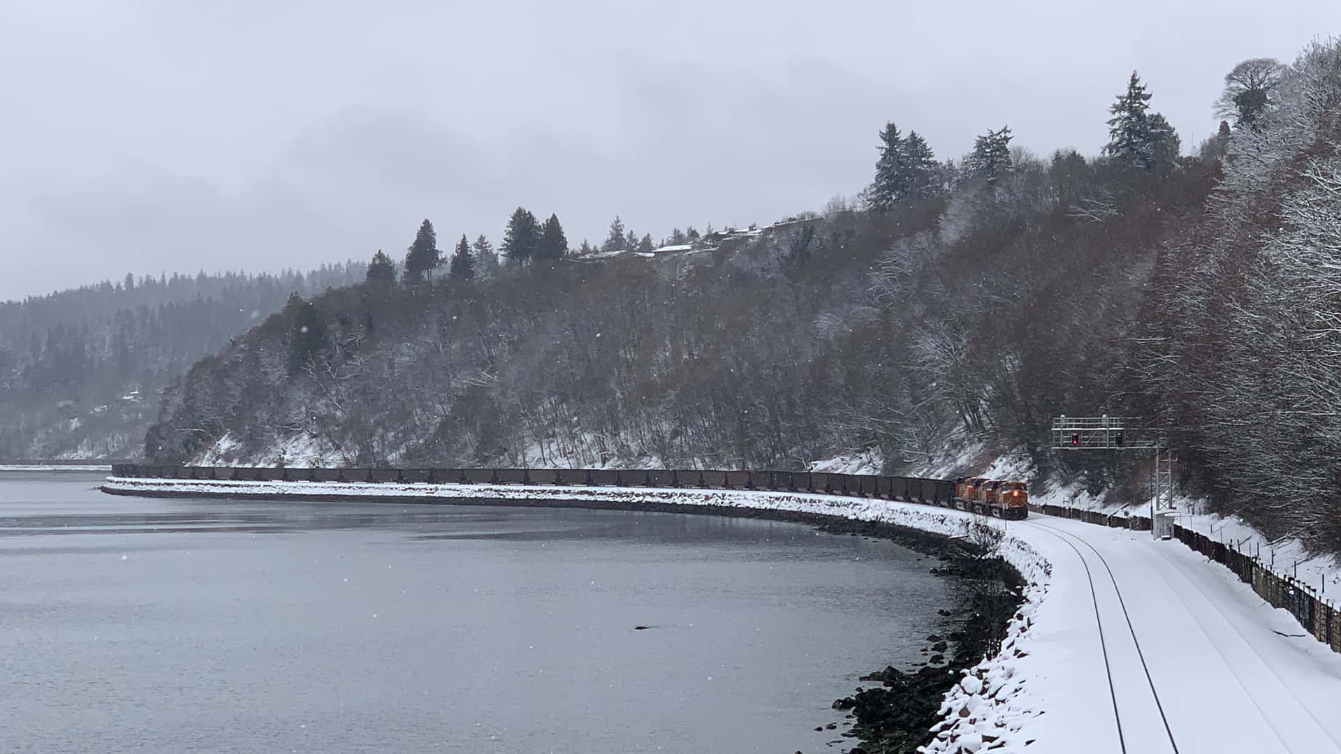 a coal train over a mile long waits at a red light in the snow