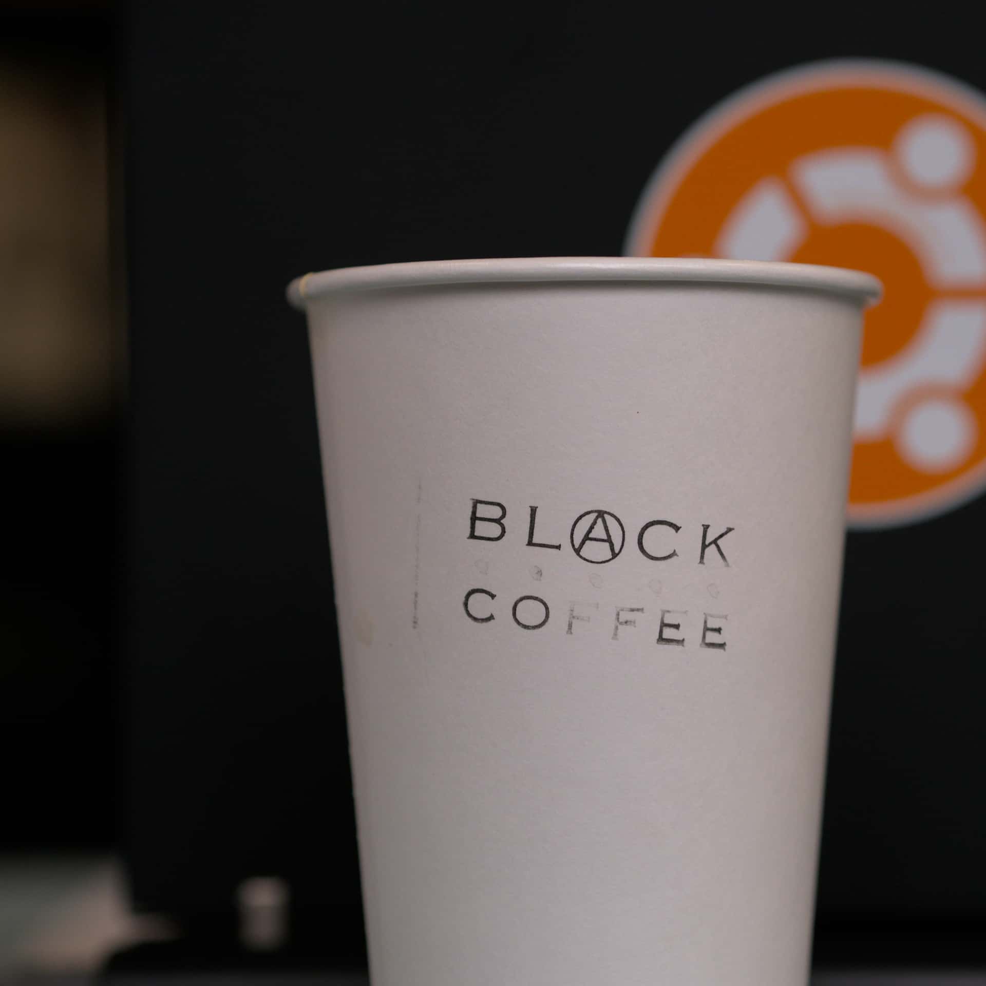 paper coffee cup stamped with the logo of Black Coffee Co-Op