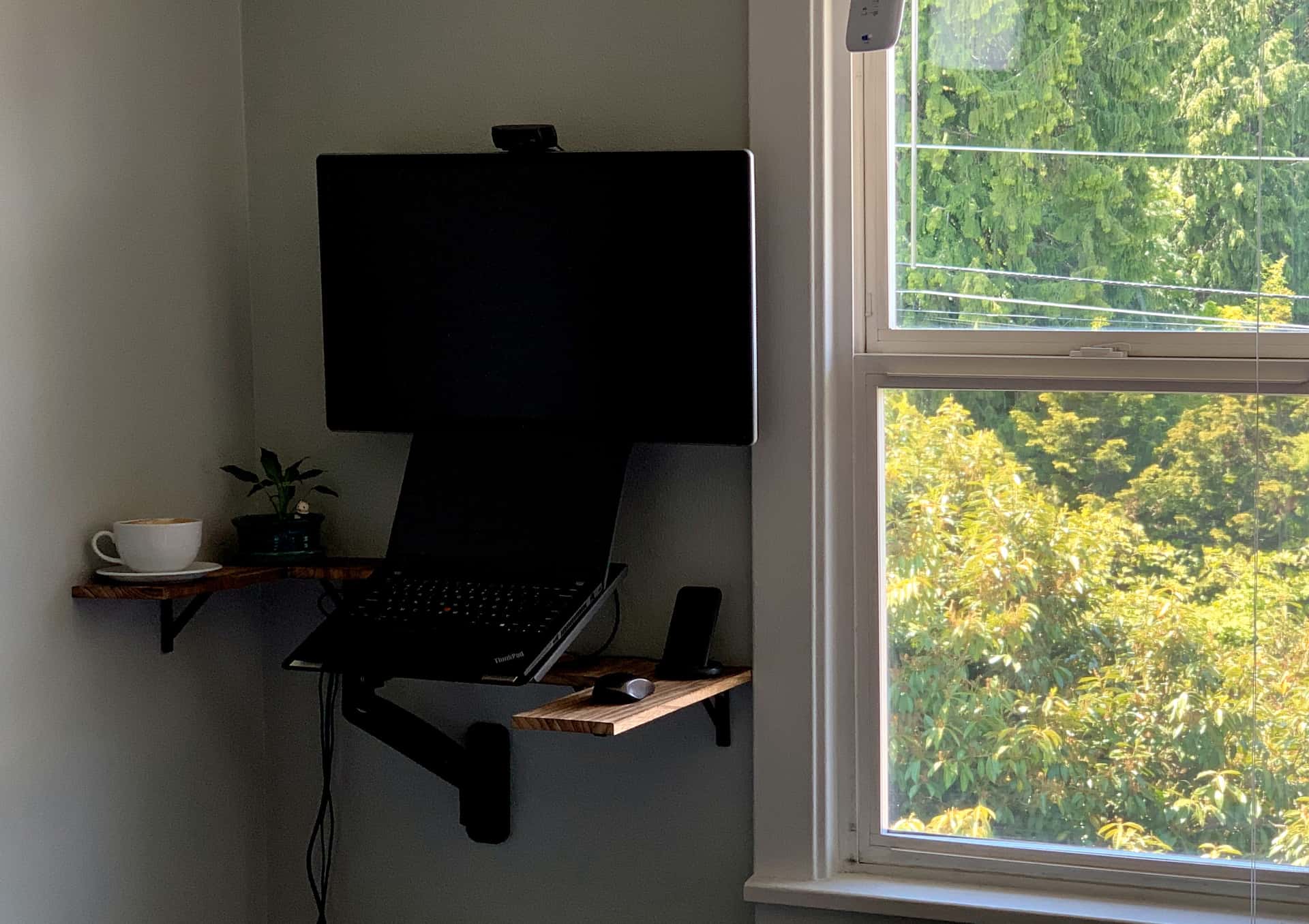 standing desk built from wall-mounted monitor, laptop stand, and shelves