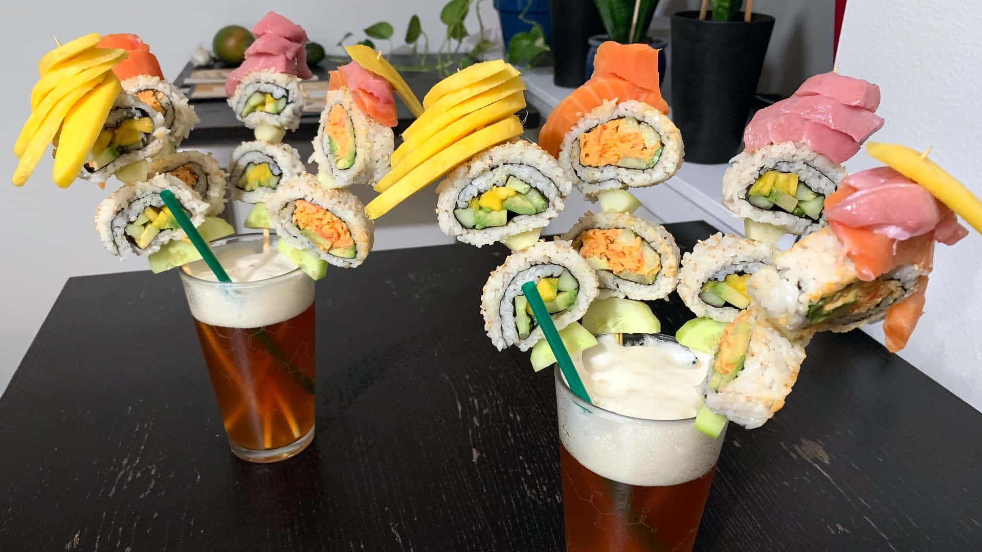bamboo skewers of sushi and mango held upright in bouquets by pints of beer