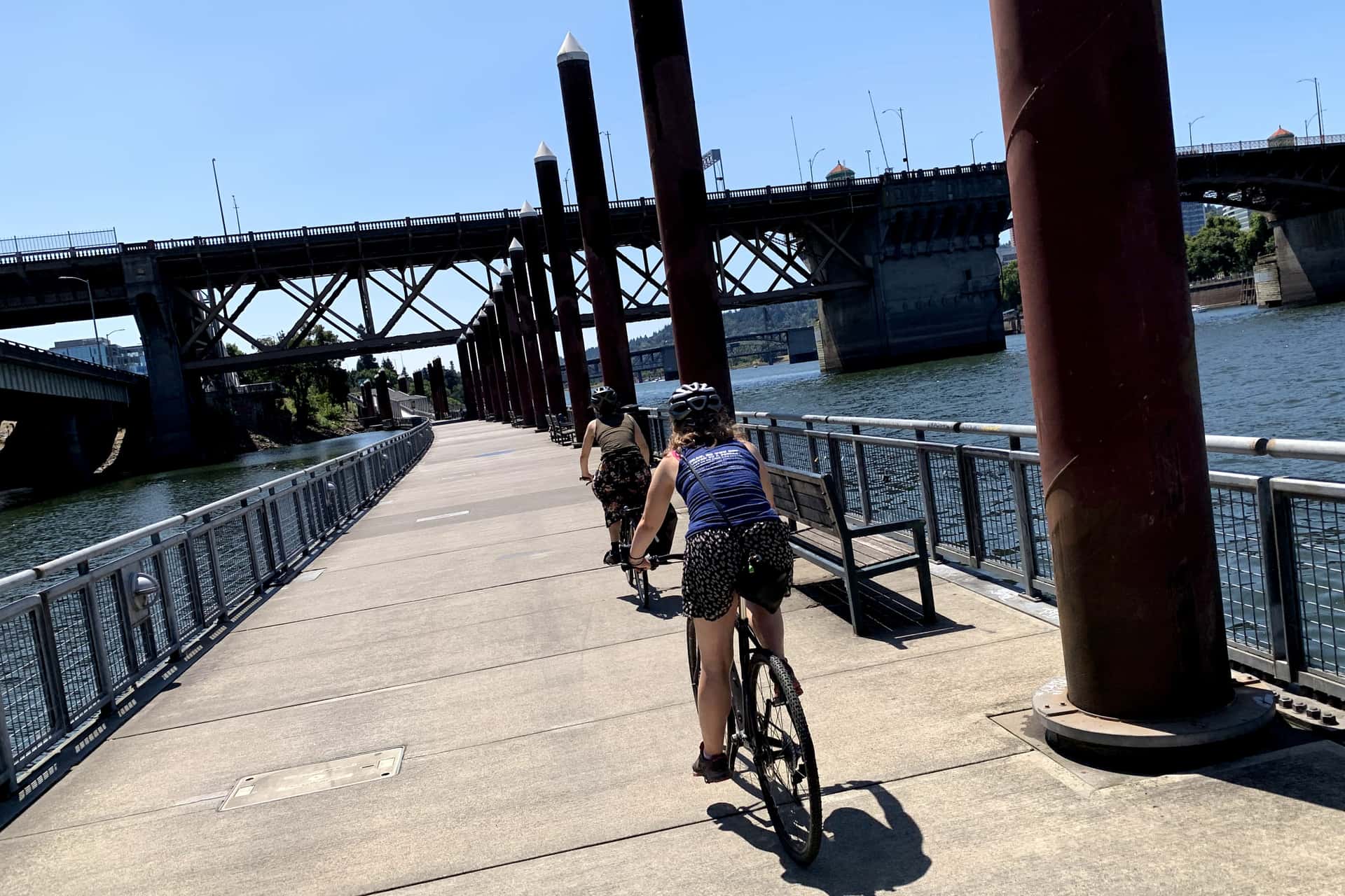 two cyclists ride along the floating section of Portland’s Eastbank Esplanade toward the Burnside Bridge