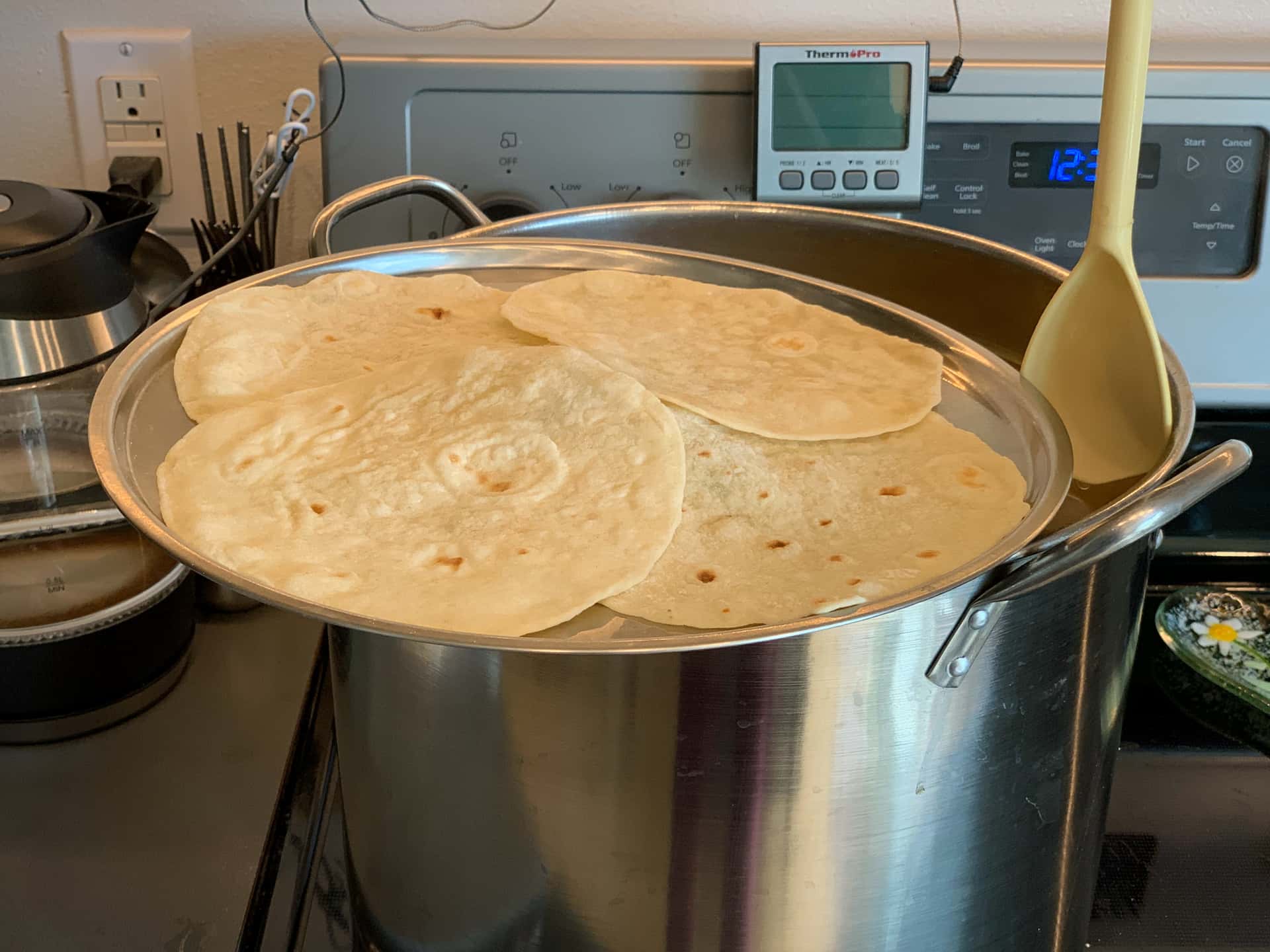 homemade tortillas warming on the lid of a homebrew boil